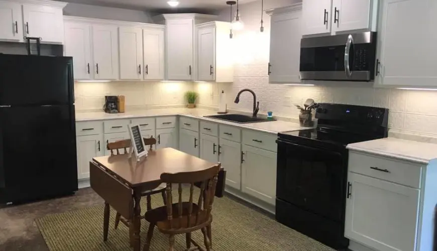 A kitchen with white cabinets and black appliances.