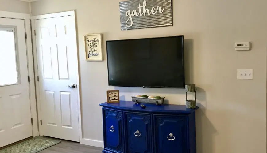 A tv mounted on the wall above a blue cabinet.