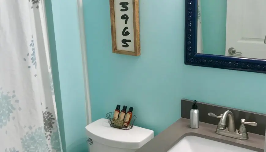 A bathroom with blue walls and white fixtures.