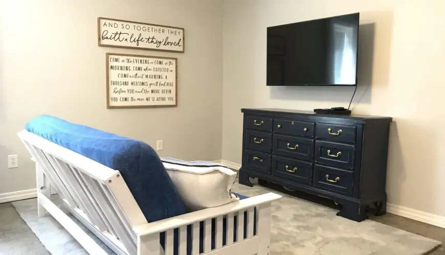 A bedroom with a bed, tv and dresser.