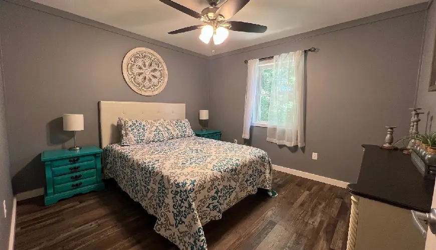 A bedroom with a bed, two nightstands and a ceiling fan.