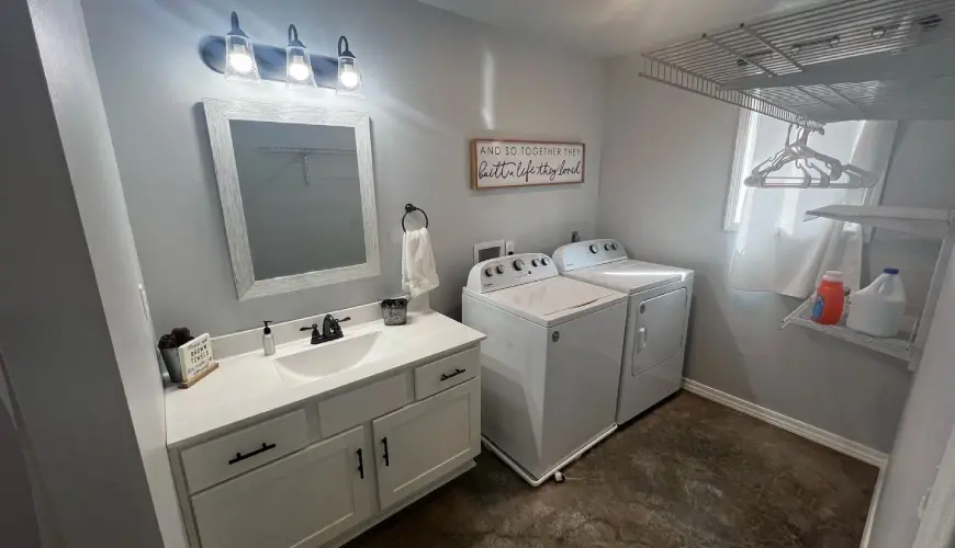 A bathroom with two white appliances and a sink.