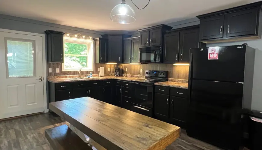 A kitchen with black cabinets and wooden island.